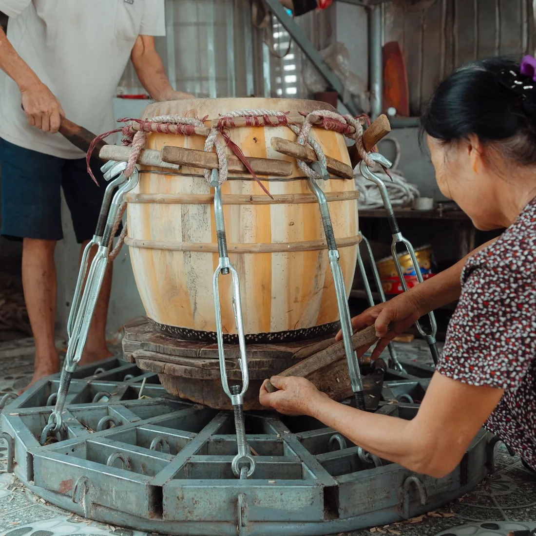 Cuerpo de duelas de madera clara sujeto por un cerco metálico durante el montaje en un taller